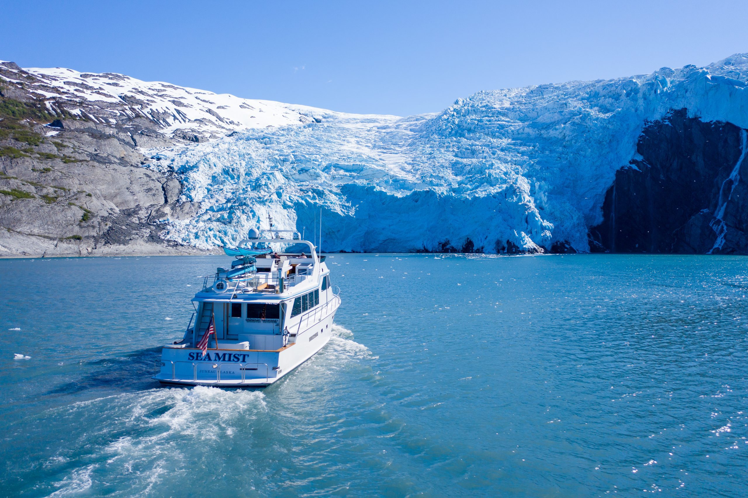 a small, luxury cruise ship, the "Sea Mist" cruising towards a tidewater glacier